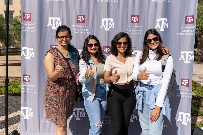 A photo of female students in front of a Grad School backdrop