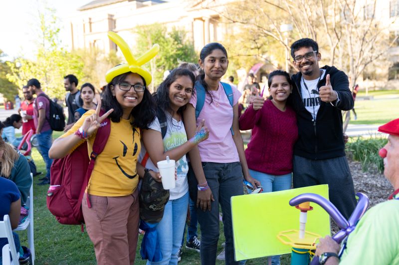 Graduate students at an outdoor event with facepaint and balloons